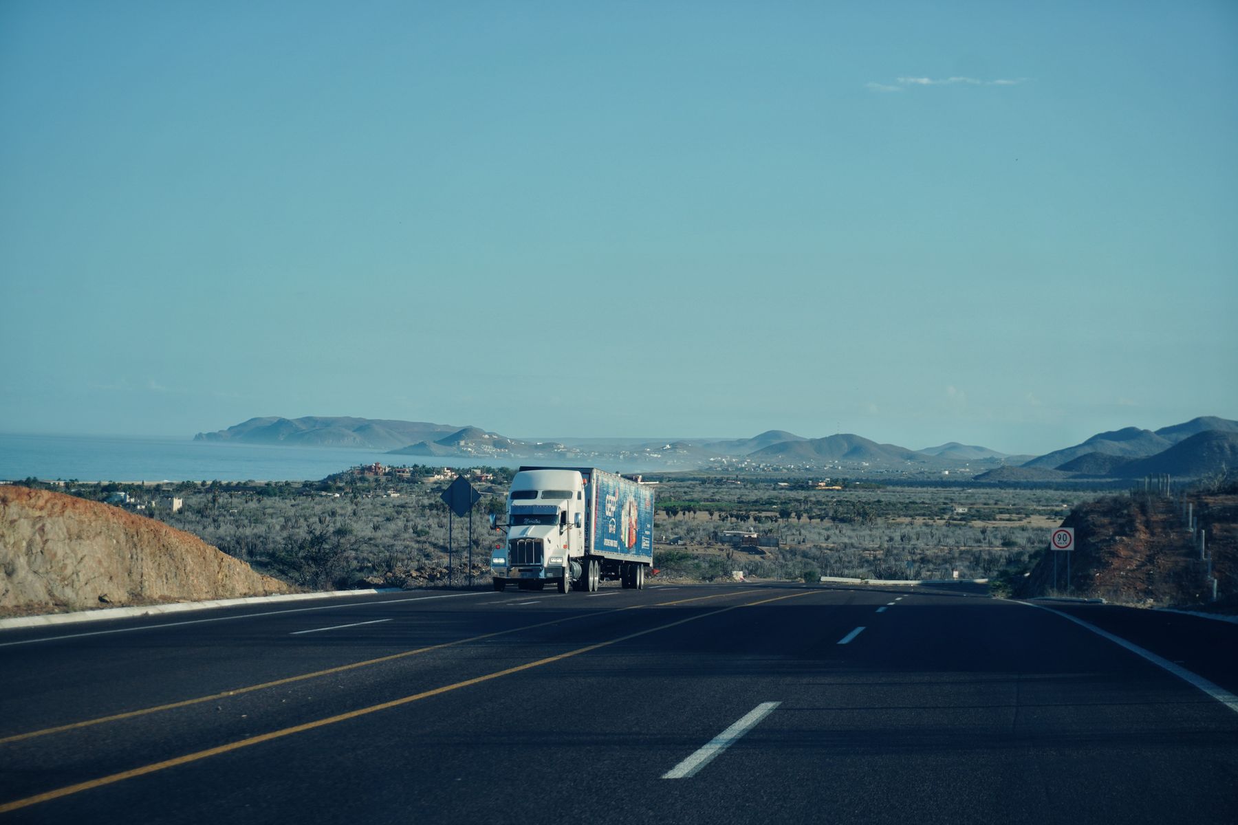 A semi truck driving away on an open highway